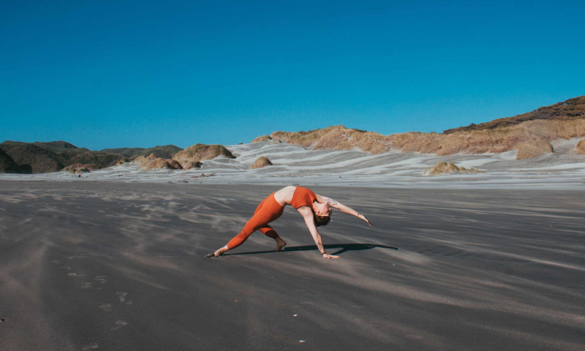 Yogaposition "Wilde Thing" auf schwarzem Strand